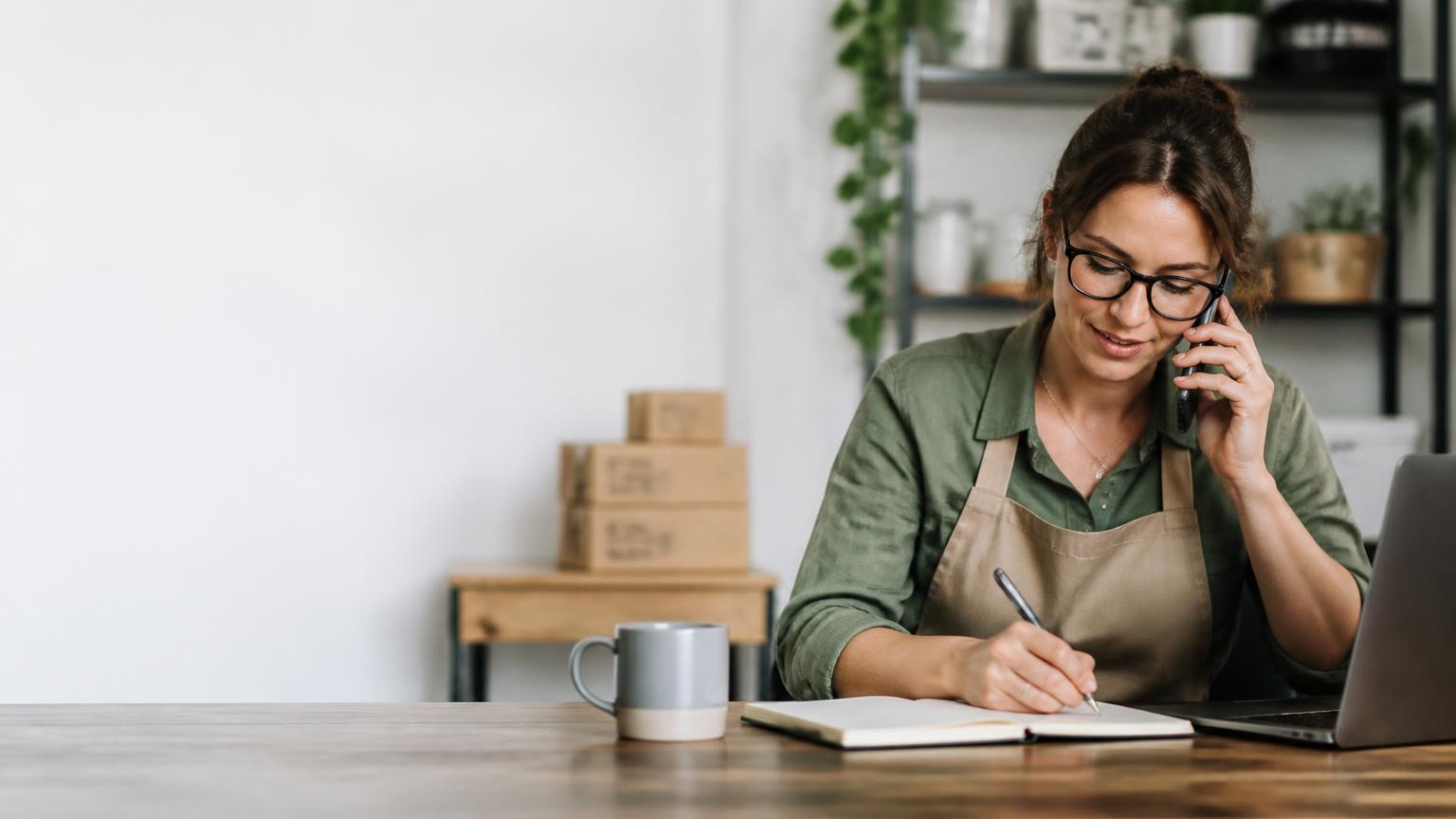 Business owner taking notes during a customer enquiry call